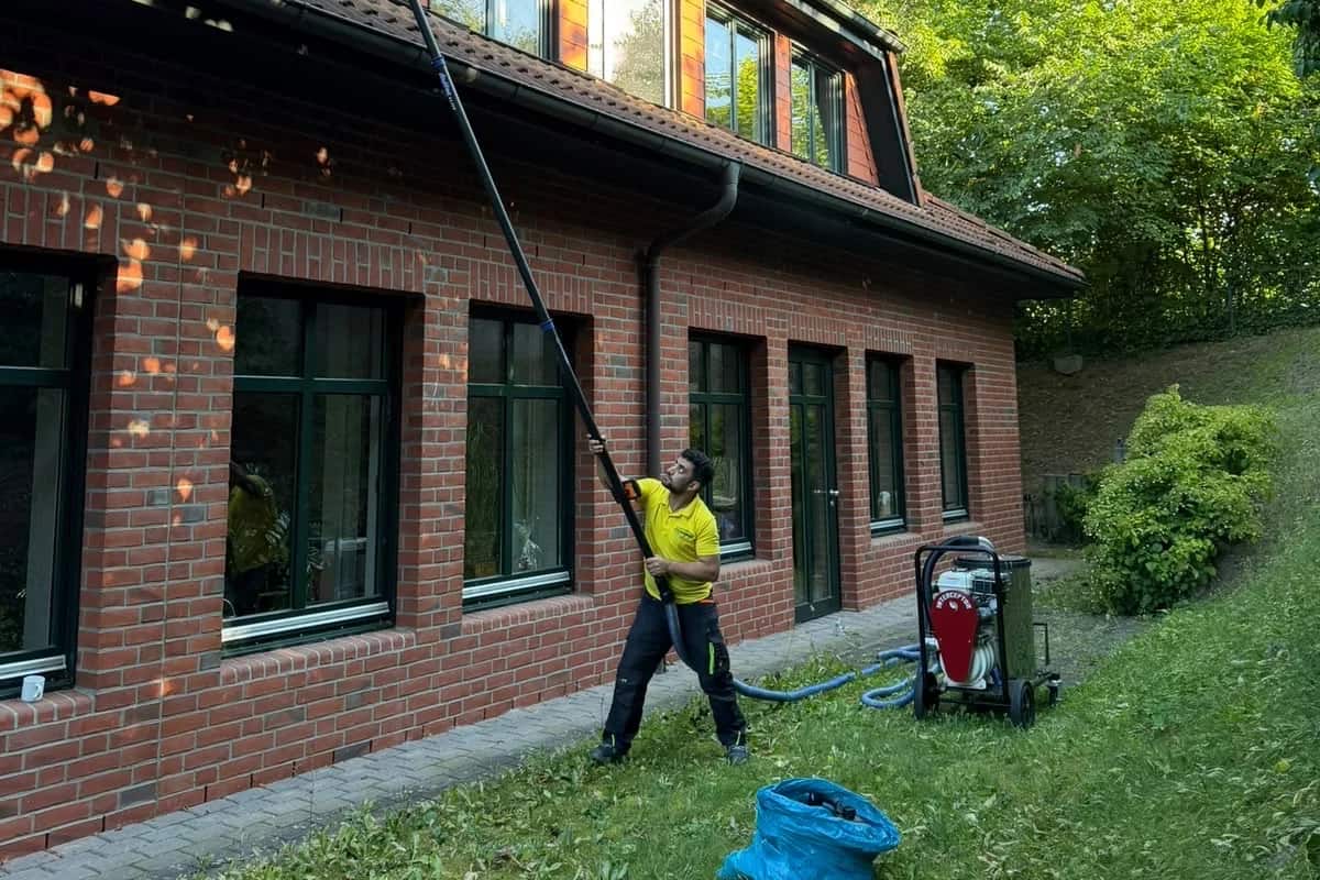 Fensterreinigung mit Teleskopstange an einem Backsteingebäude in Schleswig-Holstein durch die Blitz Gebäudereinigung