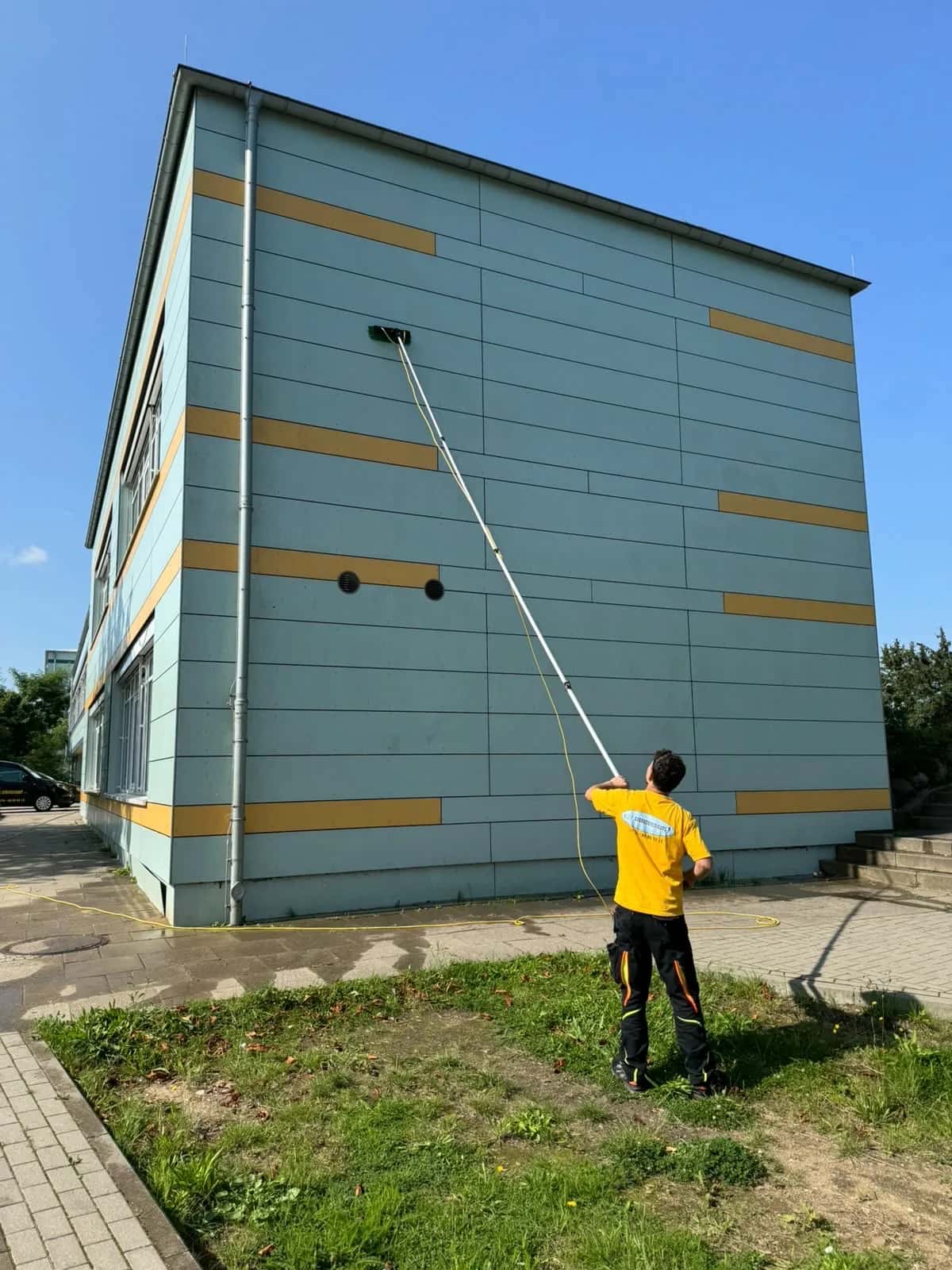 Mitarbeiter der Blitz Gebäudereinigung bei der Fassadenreinigung mit Teleskopstange in Kiel